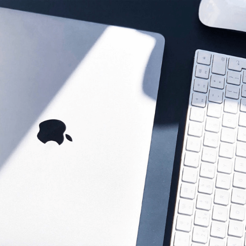 Een MacBook met een Apple toetsenbord en muis ervoor.